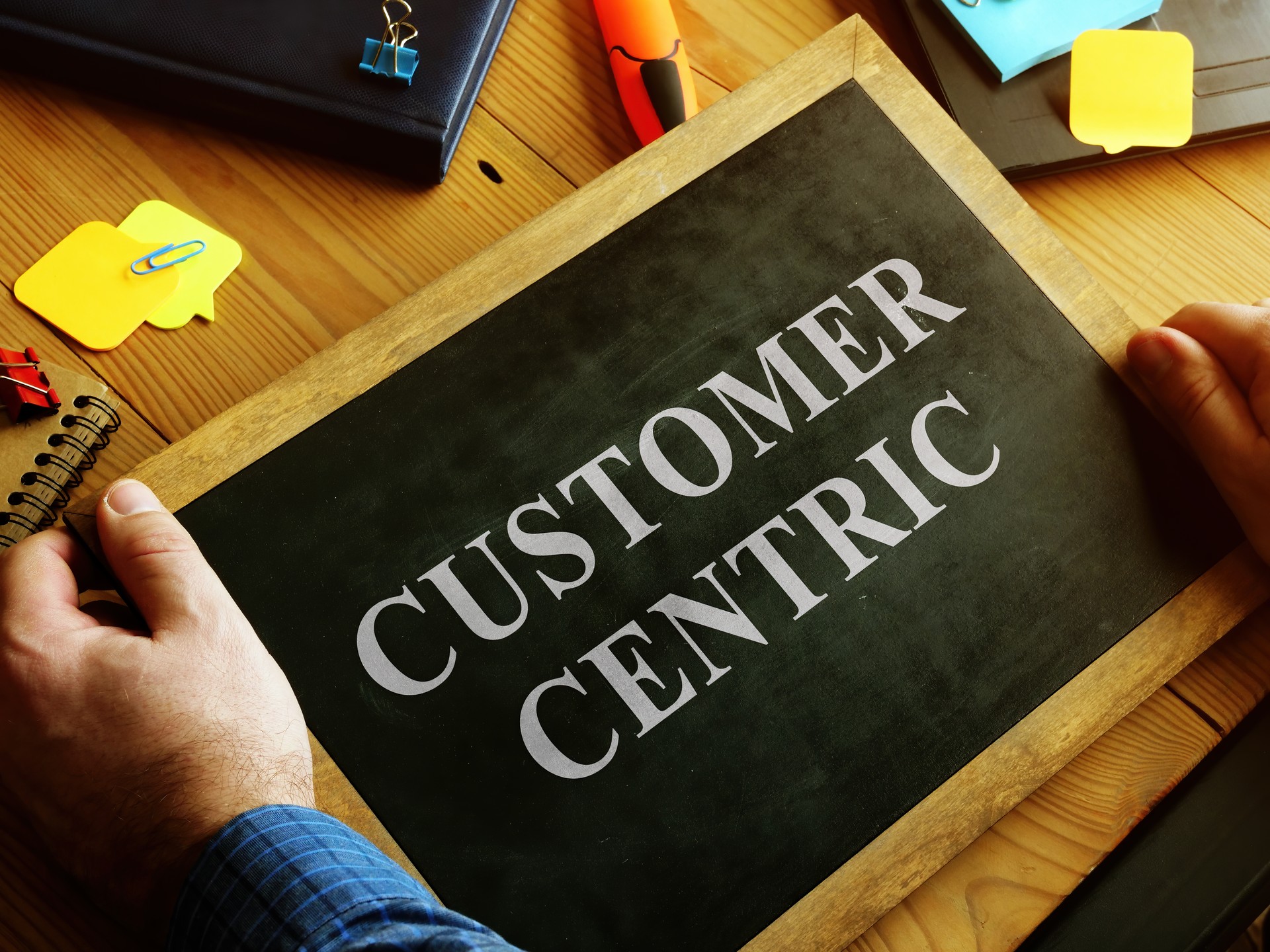 Man holding blackboard with words Customer Centric.